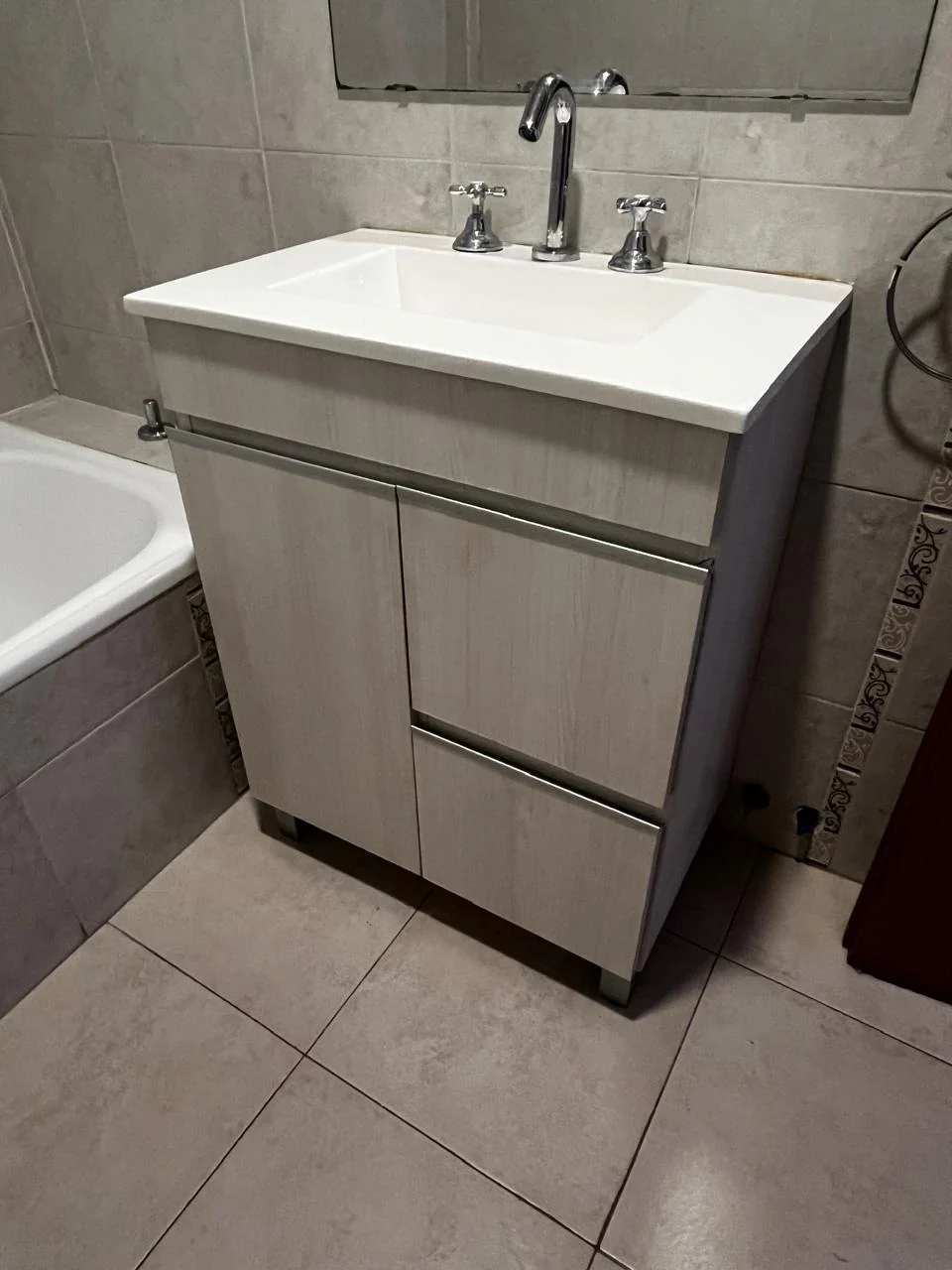 Vanitory de acabado amaderado gris claro con puerta, cajones y bacha blanca