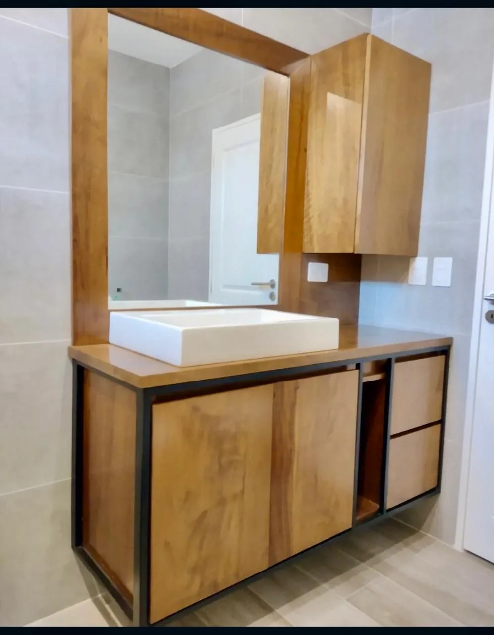 Mueble de baño con frentes de acabado madera, estructura negra y bacha rectangular blanca