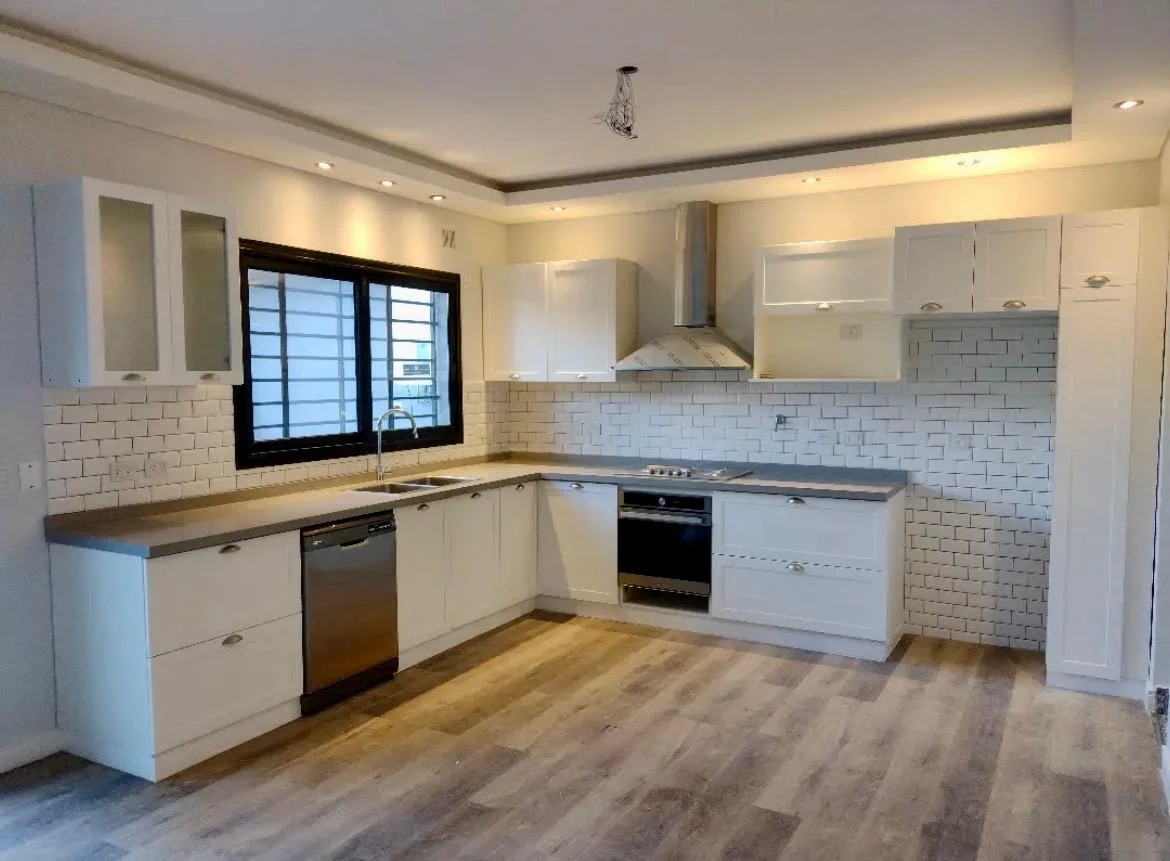 Cocina blanca con frentes enmarcados, alacenas vidriadas y distribución en L