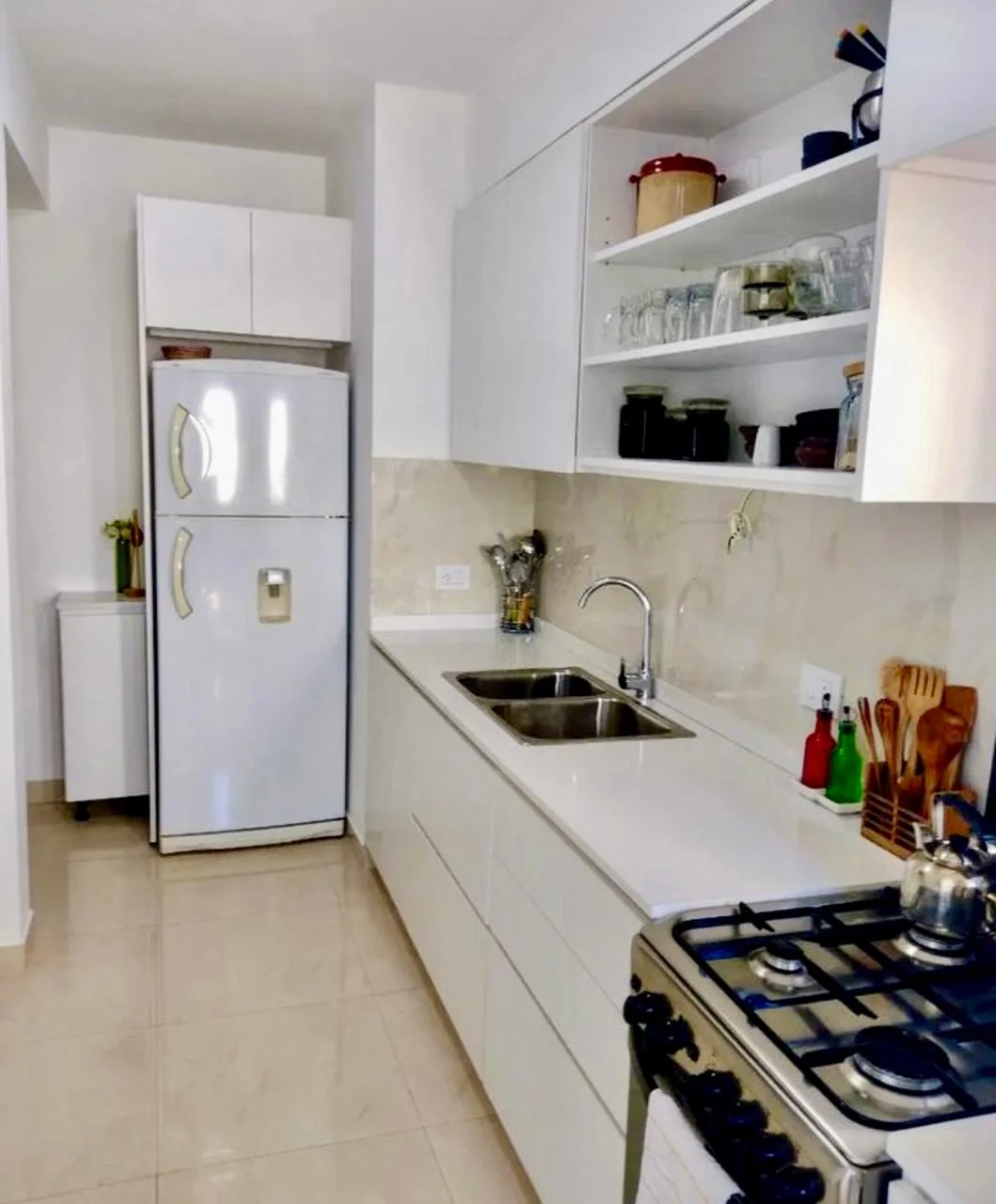 Cocina blanca de distribución lineal con estantes abiertos y bajo mesada