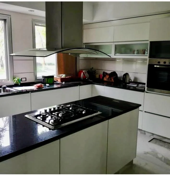 Cocina blanca con mesadas negras y anafe en el módulo central