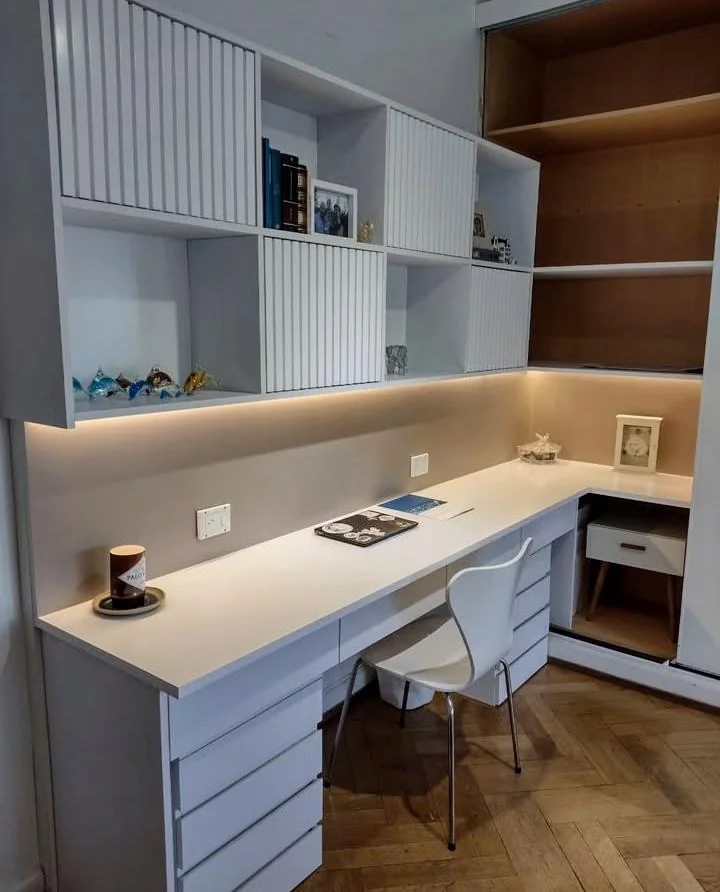 Escritorio blanco en L con estantes, puertas ranuradas e iluminación bajo los módulos
