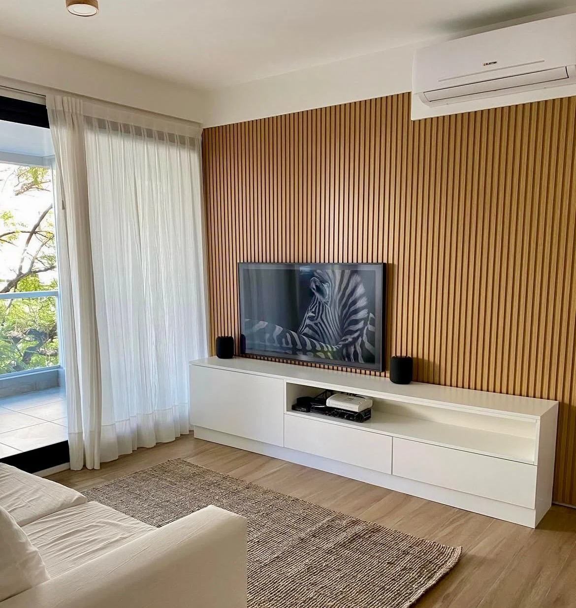 Rack blanco con panel de listones verticales en tono madera junto a una ventana
